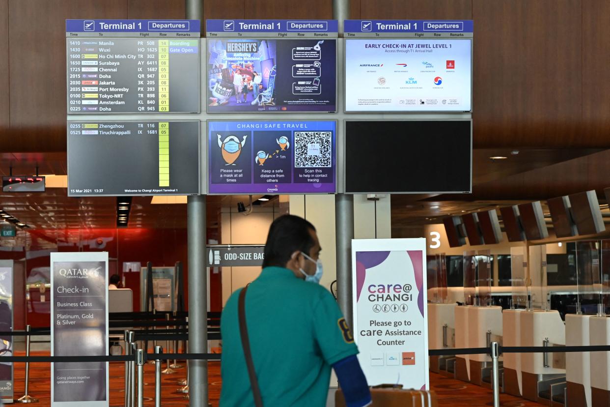 A traveller walks past flight information boards at Changi International Airport. 