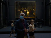 Visitors pass Rembrandt's Night Watch in the reopened Rijksmuseum in Amsterdam, Netherlands, Monday, June 1, 2020. The Dutch government took a major step to relax the coronavirus lockdown, with bars, restaurants, cinemas and museums reopening under strict conditions. (AP Photo/Peter Dejong)