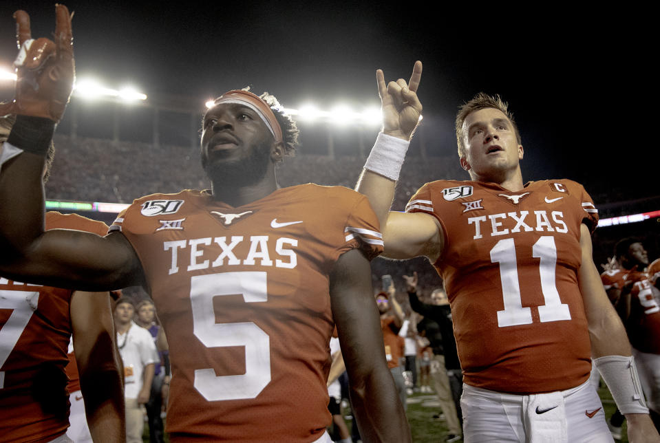 Texas defensive back D'Shawn Jamison (5) and quarterback Sam Ehlinger (11) hold up the "Hook 'em Horns" sign for the playing of "The Eyes of Texas" following Texas' 36-30 win over Oklahoma State during an NCAA college football game Saturday, Sept. 21, 2019, in Austin, Texas. (Nick Wagner/Austin American-Statesman via AP)