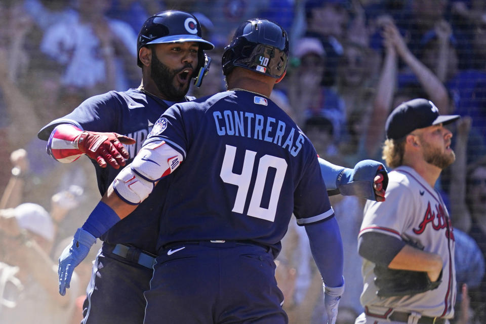 Chicago Cubs' Jonathan Villar, left, celebrates with Willson Contreras after scoring on a sacrifice fly by Christopher Morel as Atlanta Braves relief pitcher A.J. Minter, right, looks to the field during the eighth inning of a baseball game in Chicago, Friday, June 17, 2022. (AP Photo/Nam Y. Huh)