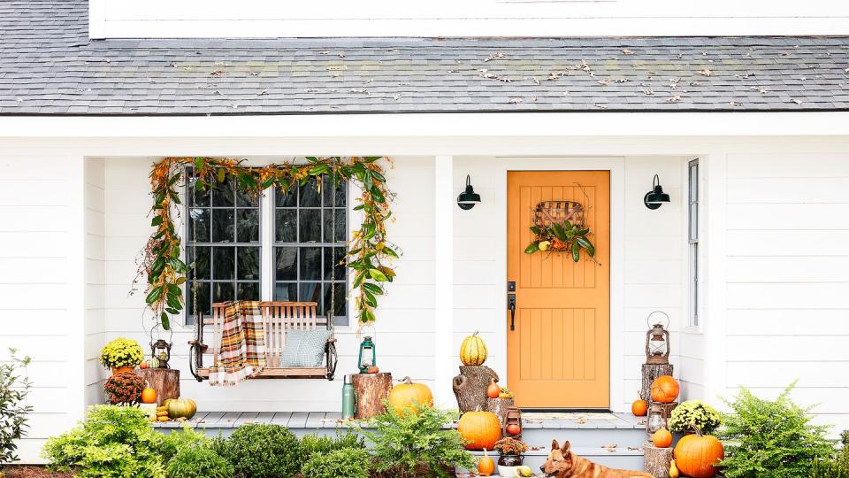 front porch with swing and orange door decorated for fall