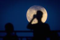 A man takes a photo of the moon one day ahead of the Supermoon phenomenon from a bridge over 42nd St. in the Manhattan borough of New York July 11, 2014. Occurring when a full moon or new moon coincides with the closest approach the moon makes to the Earth, the Supermoon results in a larger-than-usual appearance of the lunar disk.