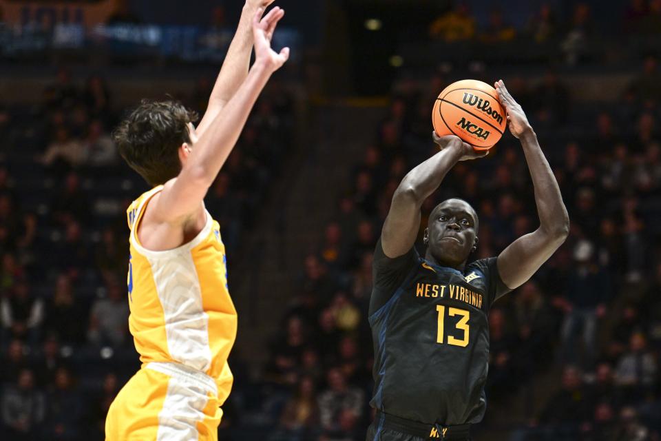 West Virginia forward Akok Akok (13) shoots while being guarded by Pittsburgh forward Guillermo Diaz Graham (25) during the first half of an NCAA college basketball game, Wednesday, Dec. 6, 2023, in Morgantown, W.V. (William Wotring/The Dominion-Post via AP)