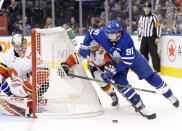 Toronto Maple Leafs center John Tavares (91) looks to wrap the puck around the net as Calgary Flames defenseman Oliver Kylington (58) and goaltender David Rittich (33) defend during the second period of an NHL hockey game Thursday, Jan. 16, 2020, in Toronto. (Nathan Denette/The Canadian Press via AP)