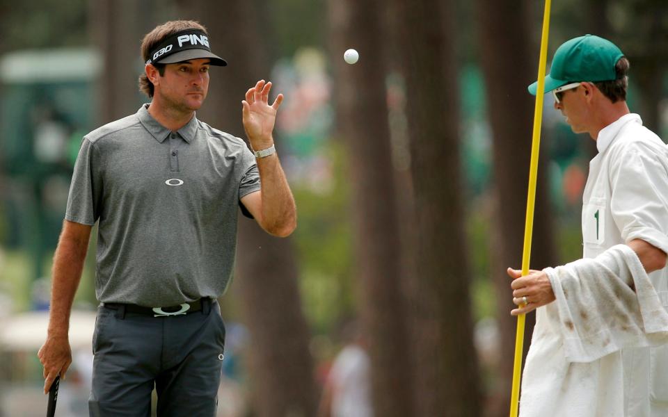 Bubba Watson of the United States retrieves his ball from his caddy on the third green during a third-round match of the Masters golf tournament at Augusta National Golf Course in Augusta, Georgia April 11, 2015