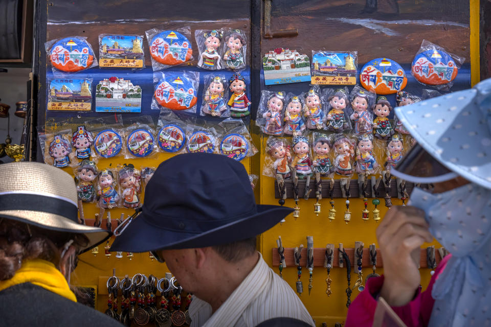 Tourists look at merchandise for sale at a souvenir shop outside of the Jokhang Temple in Lhasa in western China's Tibet Autonomous Region, Tuesday, June 1, 2021. Tourism is booming in Tibet as more Chinese travel in-country because of the coronavirus pandemic, posing risks to the region's fragile environment and historic sites. (AP Photo/Mark Schiefelbein)