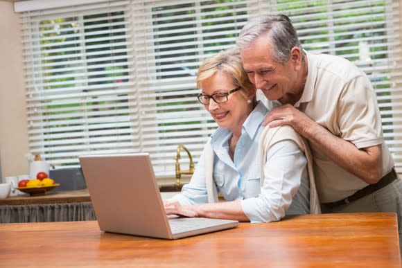 Man and woman in their sixties looking at laptop computer.