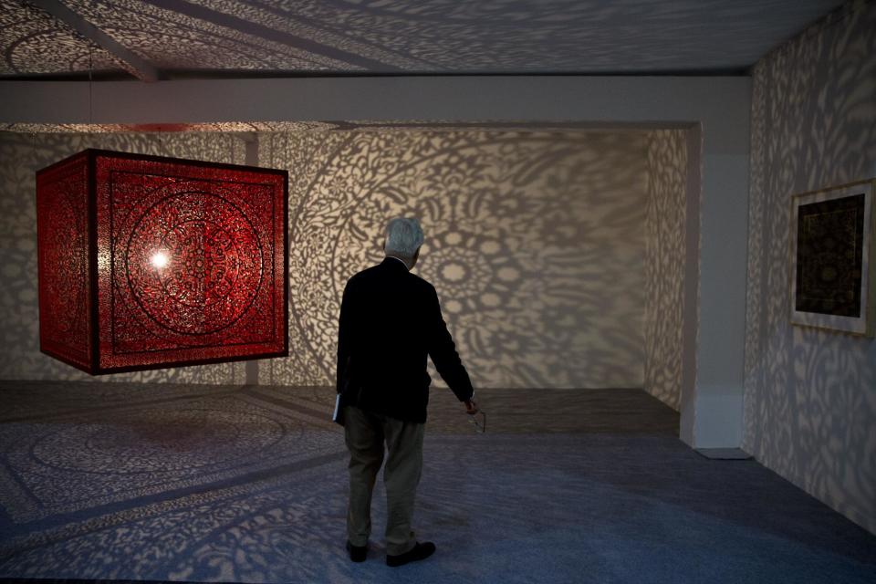A man watches an art by Anila Quayyum Agha during India Art Fair in New Delhi, India, Thursday, Feb. 2, 2017. The four day art fair brings together a number of modern and contemporary artists to present their works. (AP Photo/Tsering Topgyal)