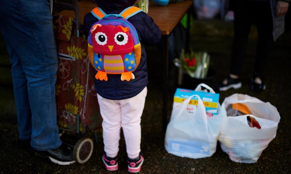 A man and his son queue to collect their food parcel at the Bread and Butter Thing in Ashton-under-Lyne, Greater Manchester