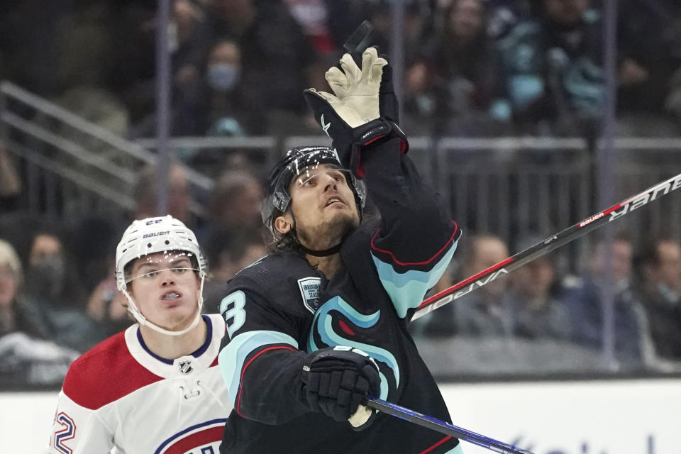 Seattle Kraken left wing Brandon Tanev (13) reaches for the puck as Montreal Canadiens right wing Cole Caufield (22) looks on during the second period of an NHL hockey game, Tuesday, Oct. 26, 2021, in Seattle. (AP Photo/Ted S. Warren)