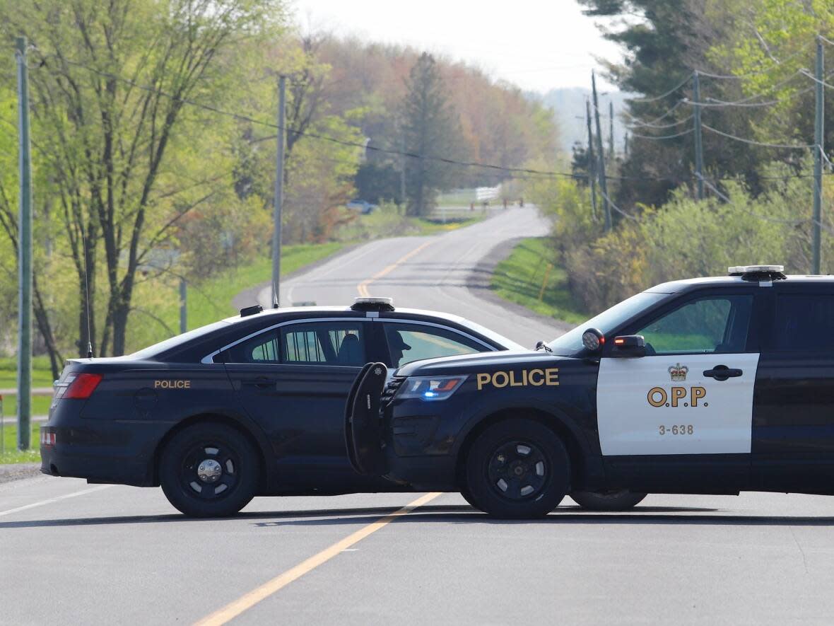 OPP vehicles block the road near the scene of a shooting where one Ontario Provincial Police officer was killed and two others were injured in Bourget on May 11. (Patrick Doyle/The Canadian Press - image credit)