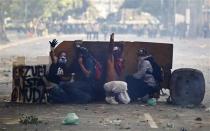 Demonstrators ask for support as they shield themselves from police during a protest against the government of President Nicolas Maduro in Caracas, February 22, 2014. REUTERS/Carlos Garcia Rawlins