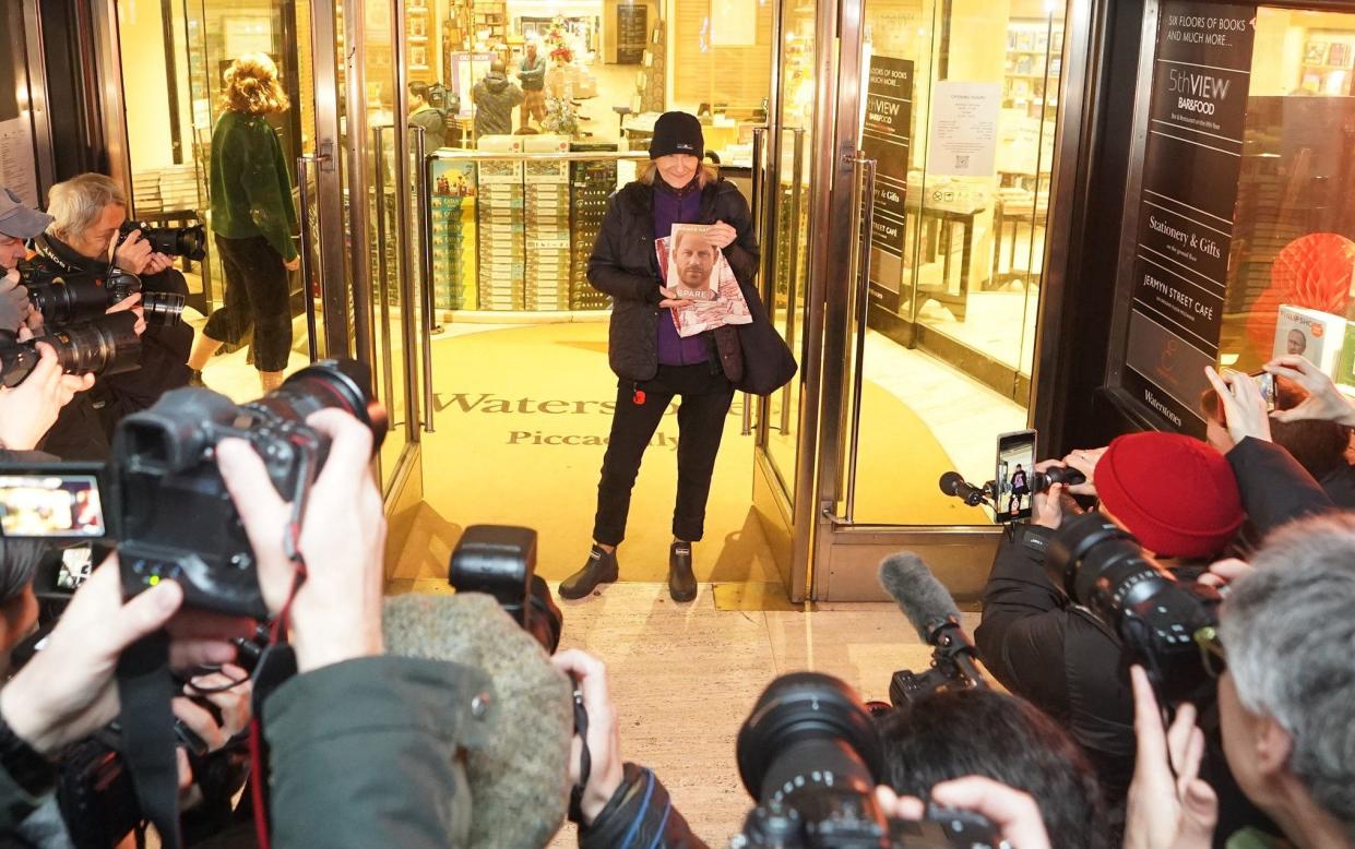 Caroline Lennon, the first customer to purchase a copy of Spare poses for photographers with her copy of the book as she leaves Waterstones Piccadilly - James Manning