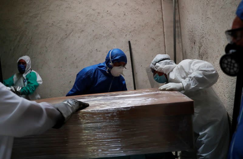 Funeral and crematorium employees work on a coffin carrying the body of a person who died from the coronavirus disease (COVID-19) before its cremation, at San Isidro crematory in Mexico City