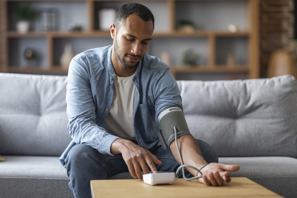 Man Sitting On Couch, Checking Blood Pressure