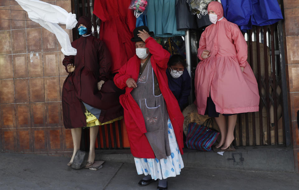 Una mujer aymara se prueba un traje en una tienda que vende ropa de protección adecuada para el estilo de vestir de las mujeres indígenas bolivianas en medio de la pandemia del nuevo coronavirus en La Paz, Bolivia, el miércoles 3 de junio de 2020. (AP Foto/Juan Karita)
