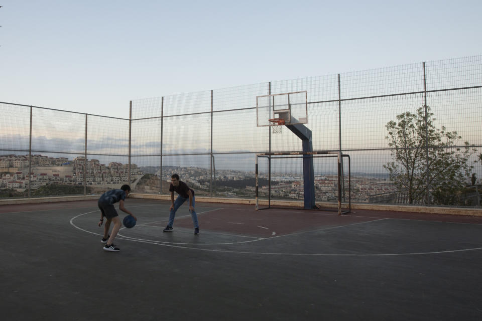 Teens play basketball in the West Bank Jewish settlement of Efrat, Tuesday, March 16, 2021. Israel went on an aggressive settlement spree during the Trump era, according to an AP investigation, pushing deeper into the occupied West Bank than ever before and putting the Biden administration into a bind as it seeks to revive Mideast peace efforts. (AP Photo/Maya Alleruzzo)