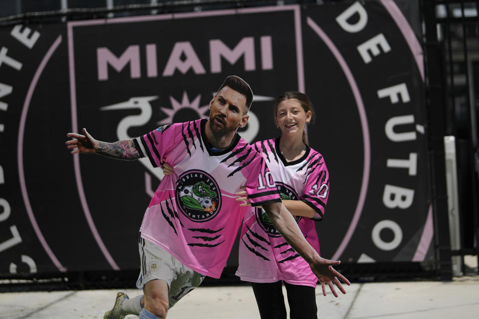 FILE - Lis Moyano, 13, of Aventura, Fla., carries a cardboard cutout of Argentine soccer superstar Lionel Messi as a group of South Florida fans waits outside DRV PNK Stadium, home of Inter Miami MLS soccer club, in hopes of catching a glimpse of Messi, Tuesday, July 11, 2023, in Fort Lauderdale, Fla. While Messi's immediate impact is off-the-charts, it remains to be seen whether fans will be wooed to the league as a whole.(AP Photo/Rebecca Blackwell, File)