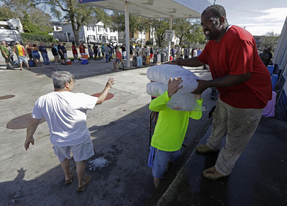 FILE - In this Sept. 18, 2018, file photo, employees of Rose Ice and Coal Co. distribute bags of ice to customers in Wilmington, N.C. Many in Wilmington woke up Wednesday suddenly very tired. The days-long scavenger hunt for gas and ice was over as stores opened and relief agencies were able to roll into the city. (AP Photo/Chuck Burton, File)