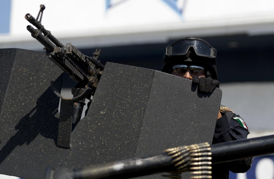 A federal police patrols the entrance to Apatzingan, Mexico, Tuesday, Jan. 14, 2014. Mexican soldiers and federal police kept a tense standoff with vigilantes Tuesday after a new government campaign to stop violence in the western Michoacan state turned deadly. A clash occurred as the government sent more troops to where the vigilantes have been fighting the Knights Templar cartel. Federal and state officials met late Tuesday with leaders of vigilante groups but failed to reach a disarmament agreement. (AP Photo/Eduardo Verdugo)