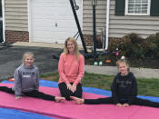 Jamie Burton, of Glen Allen, Va., and her two daughters, Josie, 12, left, and Cayden, 9, right, outside their home Thursday, March 26, 2020 on gymnastics mats. The Burtons have had more time together because the girls’ nightly gymnastics practices have been canceled because of the coronavirus outbreak. (AP Photo/Denise Lavoie)