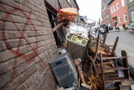 A pile of discarded furniture stands in front of a house in the district of Blessem, in Ergfstadt, Germany, Thursday July 22, 2021. In the flood disaster area of Erftstadt-Blessem, some residents are being allowed back into their homes to clear debris after heavy rains caused devastating floods. (Marius Becker/dpa via AP)