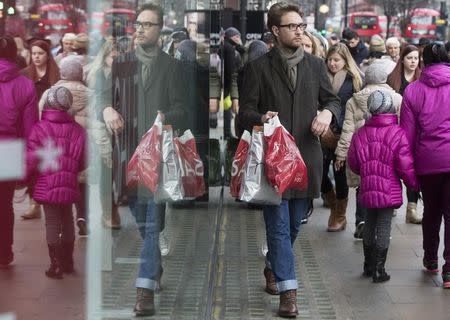 File photo of a shopper is reflected in a store window on Oxford Street in central London December 30, 2014. REUTERS/Neil Hall