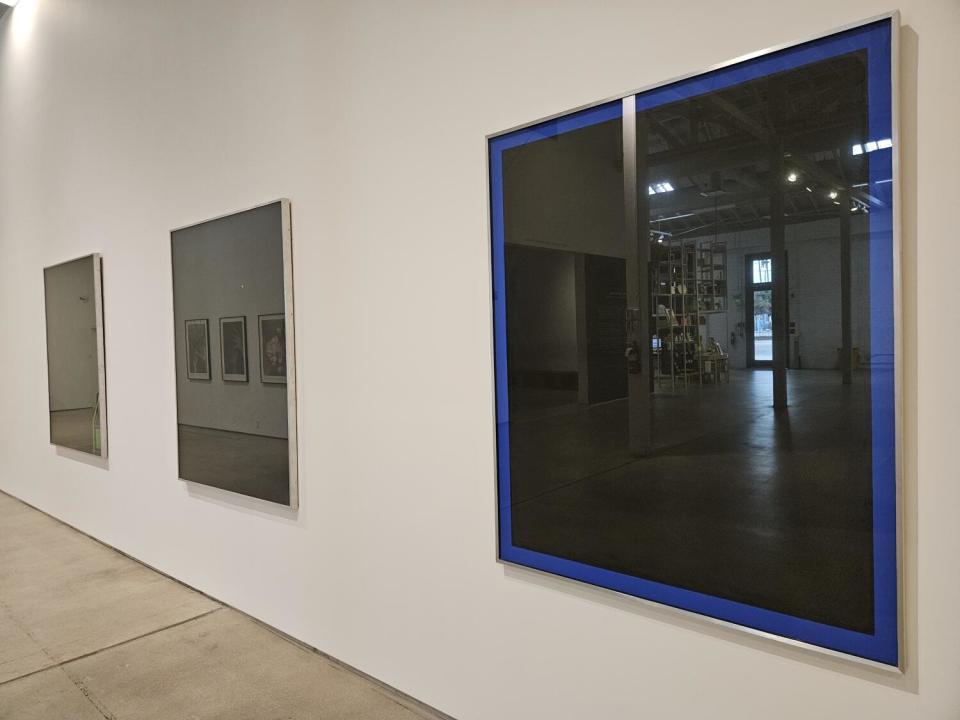 Black glass paintings reflect their museum surroundings.