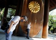 A visitor wearing a protective face mask bows his heads toward the main shrine as he visits to pay tribute to the war dead at Yasukuni Shrine ahead of the anniversary of Japan's surrender in World War Two in Tokyo