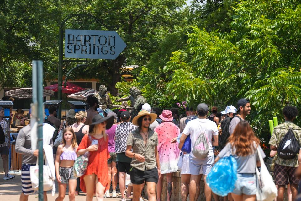 Hundreds wait in line to get into Barton Springs Pool amid scorching conditions Monday.