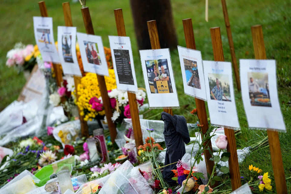 Rain soaked memorials for those who died sit along the roadside by Schemengees Bar & Grille, Monday, Oct. 30, 2023, in Lewiston, Maine. Investigators are still searching for a motive for the massacre that claimed 18 lives as the community seeks a return to normalcy. (AP Photo/Matt York)