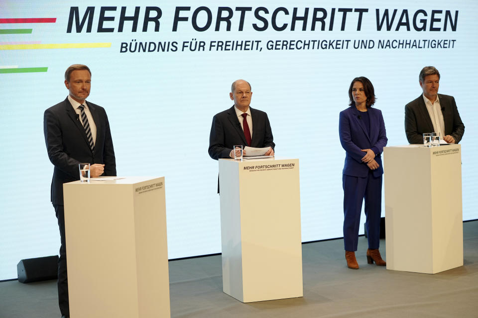 Social Democratic Party, SPD, chancellor candidate Olaf Scholz, second left, stands with the Green party leaders Annalena Baerbock, third from left, Robert Habeck, right, and the Free Democratic Party chairman Christian Lindner, left, at a joint news conference in Berlin, Germany, Wednesday, Nov. 24, 2021. After weeks of negotiations the leaders of the three parties present a coalition contract for a new German government. (Michael Kappeler/dpa via AP)