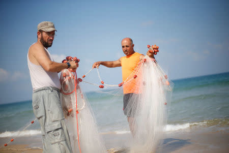 Palestinian fisherman Jihad al-Soltan (R) prepares his fishing net on a beach in the northern Gaza Strip August 21, 2017. REUTERS/Mohammed Salem