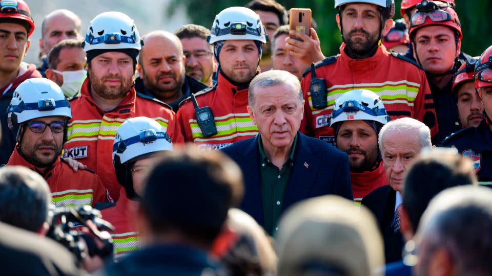 Turkish President Recep Tayyip Erdogan stands with rescue workers as he visits the hard-hit southeastern province of Hatay, on February 20, 2023. - Yasin Akgul/AFP/Getty Images