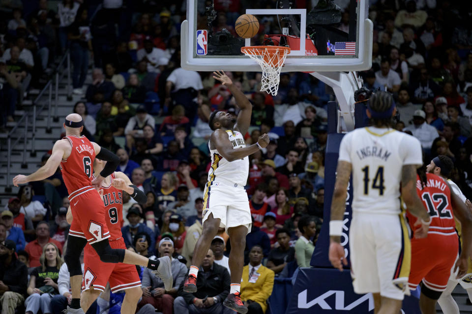 New Orleans Pelicans forward Zion Williamson (1) makes a basket against Chicago Bulls guard Alex Caruso (6) and center Nikola Vucevic (9) during the first half of an NBA basketball game in New Orleans, Sunday, Feb. 25, 2024. (AP Photo/Matthew Hinton)