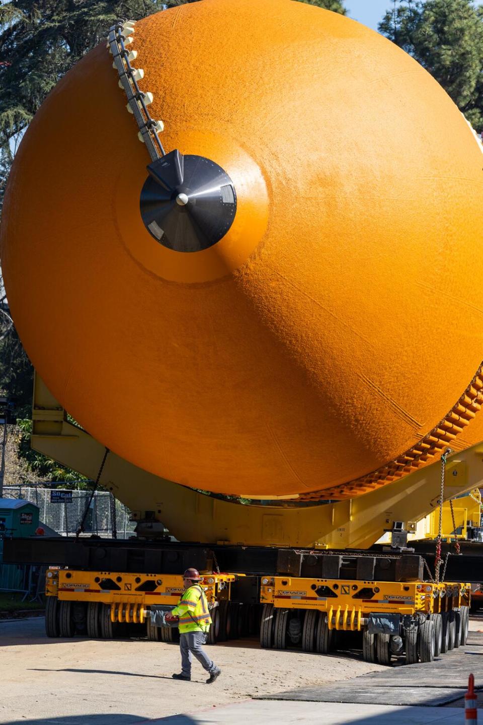 A crew member is dwarfed by the tank of the space shuttle ET-94 at the California Science Center.