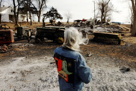 Kay Rottmayer, 65, looks at farm equipment that was destroyed by wildfires near Knowles, Oklahoma, U.S., March 14, 2017. REUTERS/Lucas Jackson