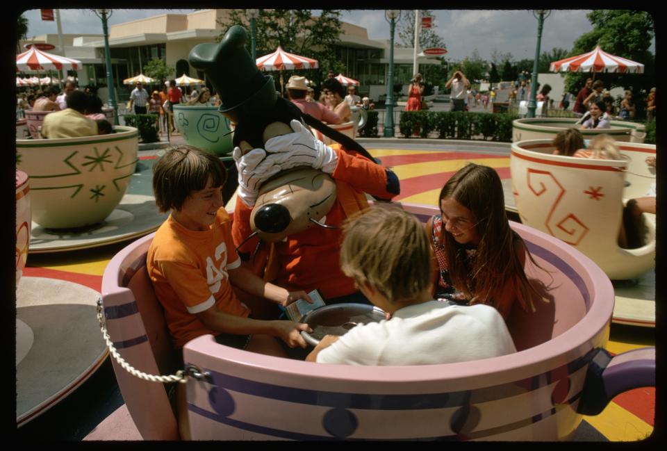 Children and a Goofy character on the Mad Tea Party ride in Walt Disney World, 1970s.