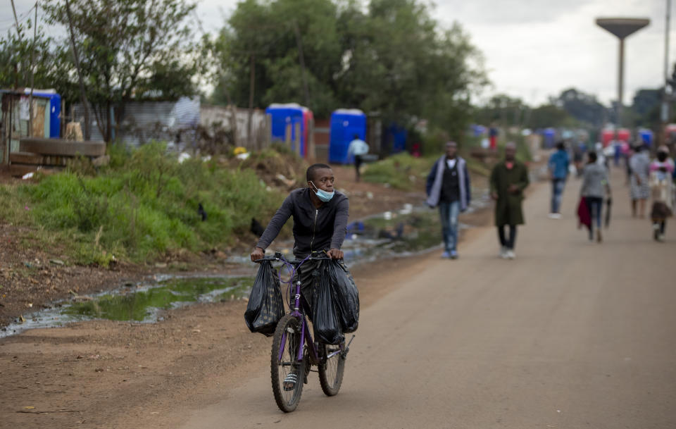 A man wearing a face mask to protect against coronavirus, cycles on the street in Thokoza, east of Johannesburg, South Africa, Friday, April 3, 2020. South Africa went into a nationwide lockdown for 21 days in an effort to control the spread of the coronavirus. The new coronavirus causes mild or moderate symptoms for most people, but for some, especially older adults and people with existing health problems, it can cause more severe illness or death. (AP Photo/Themba Hadebe)