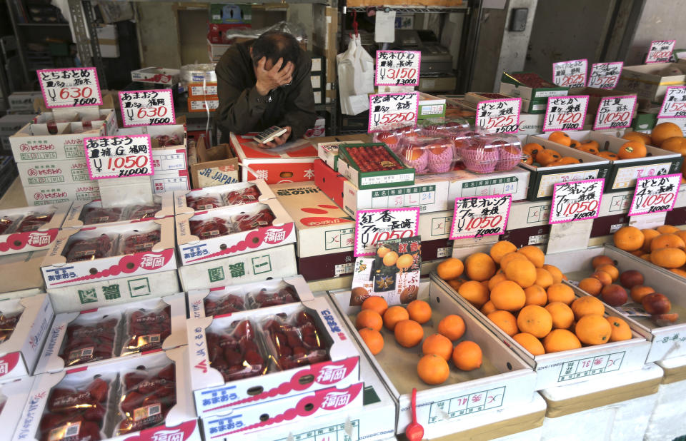 A fruits shop clerk waits for customers at Tsukiji fish market in Tokyo, Friday, March 28, 2014. Japanese household spending fell 1.5 percent in February from a year earlier, suggesting consumers are tightening belts ahead of an April 1 hike in the country's sales tax. The government also reported Friday, March 28 that core consumer prices rose 1.3 percent in February, though a large share of the increase was due to rising energy costs. (AP Photo/Eugene Hoshiko)