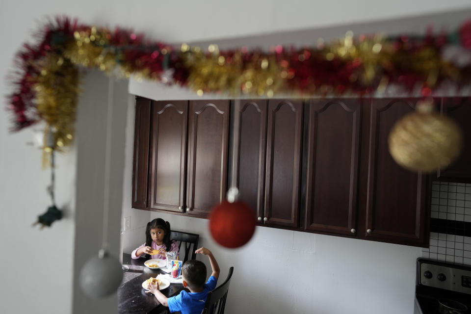 Alexa Llanos, 7, eats lunch along with little brother Alexis, 3, in the home the Llanos family moved into in October 2023, five years after fleeing Venezuela to Colombia to escape death threats and political persecution, in Lehigh Acres, Fla., Dec. 27, 2023. The family is among the first migrants allowed into the U.S. under the Biden administration's new "safe mobility offices," intended to streamline the U.S. refugee process so migrants don't give up and pay smugglers to make the journey north. (AP Photo/Rebecca Blackwell)