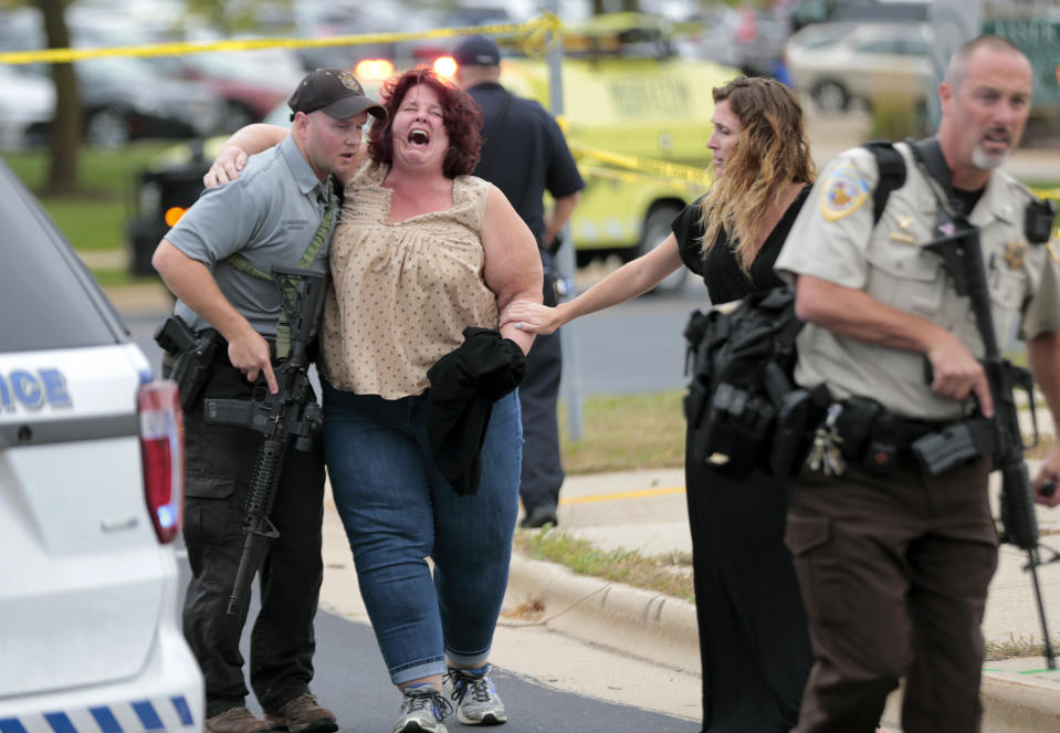 A woman is escorted from the scene of a shooting at a software company in Middleton, Wis., Wednesday, Sept. 19, 2018. Four people were shot and wounded during the shooting in the suburb of Madison, according to a city administrator. (Steve Apps/Wisconsin State Journal via AP)