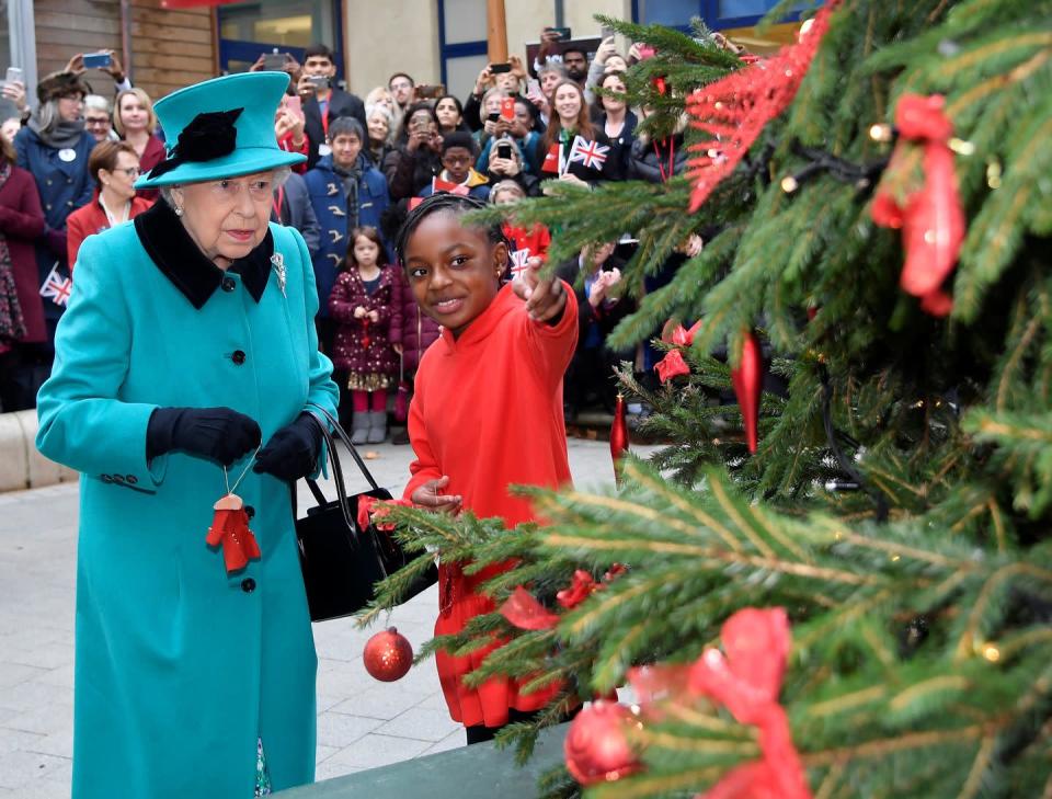 <p>Her Majesty helps an 8-year-old girl decorate a tree during the special opening of the Queen Elizabeth II Centre in London. She was paying a visit to Coram, England's oldest children's charity. </p>
