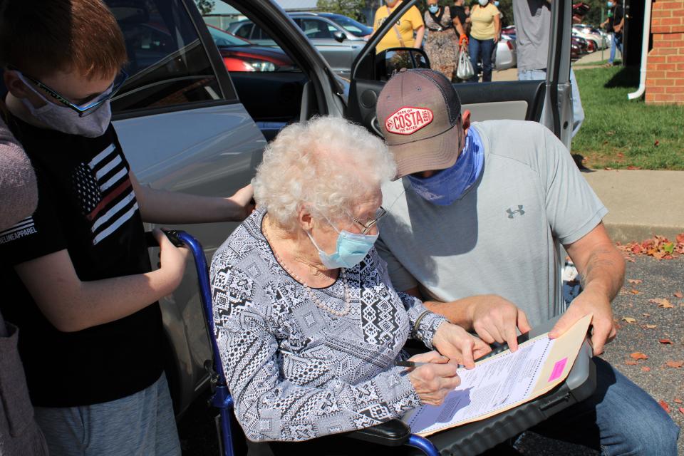 Centenarian Mabel Dorothy Duty Cook of Chesterfield with her grandson Curtis Litton's assistance fills out her ballot while her great-grandson Jack Litton looks on at the Registrar's Office in Chesterfield on Oct. 15, 2020.