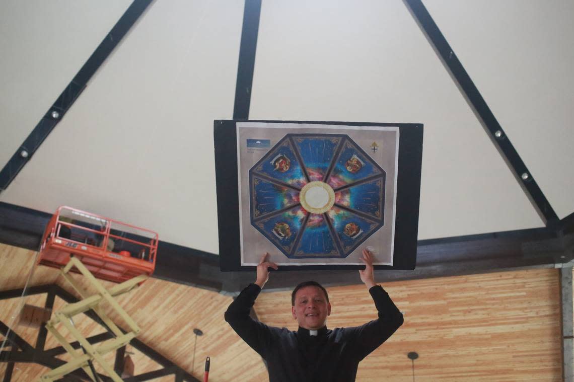  Pastor Fr. Alex Chávez under the St. Charles Borromeo Church’s dome holding a replica of the mural that will be cover the dome.