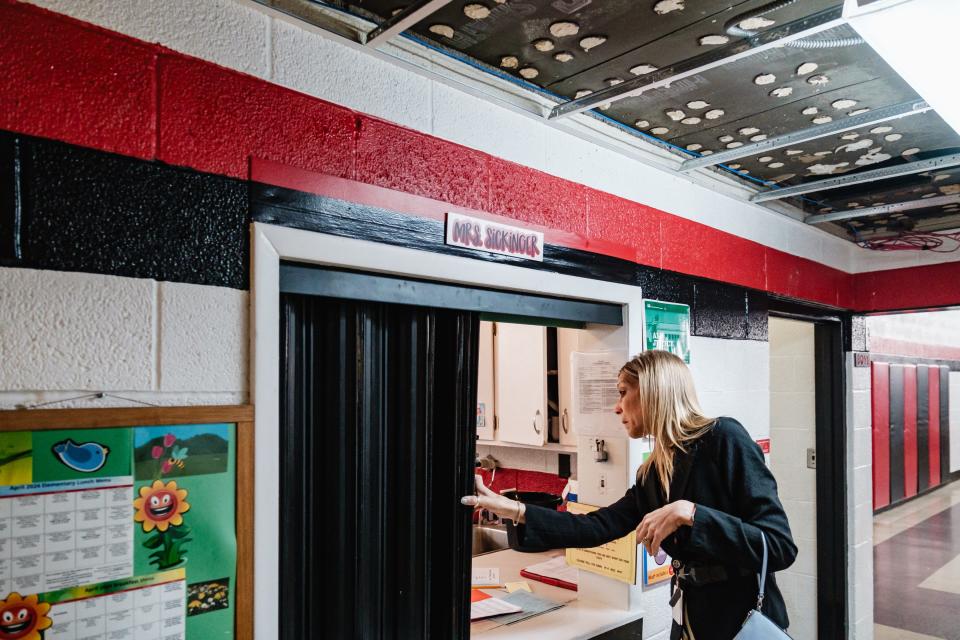 Amy Wentworth, superintendent of New Philadelphia Schools, opens the window to the kitchen at Central Elementary School, where a roof leak had caused damage, as seen above Wentworth.