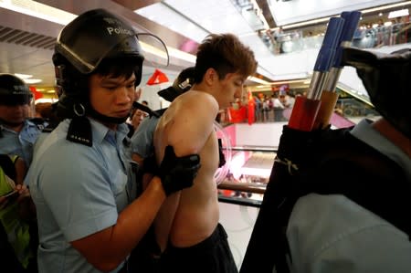 A protester is detained by the police officers at Amoy Plaza shopping mall in Kowloon Bay, Hong Kong