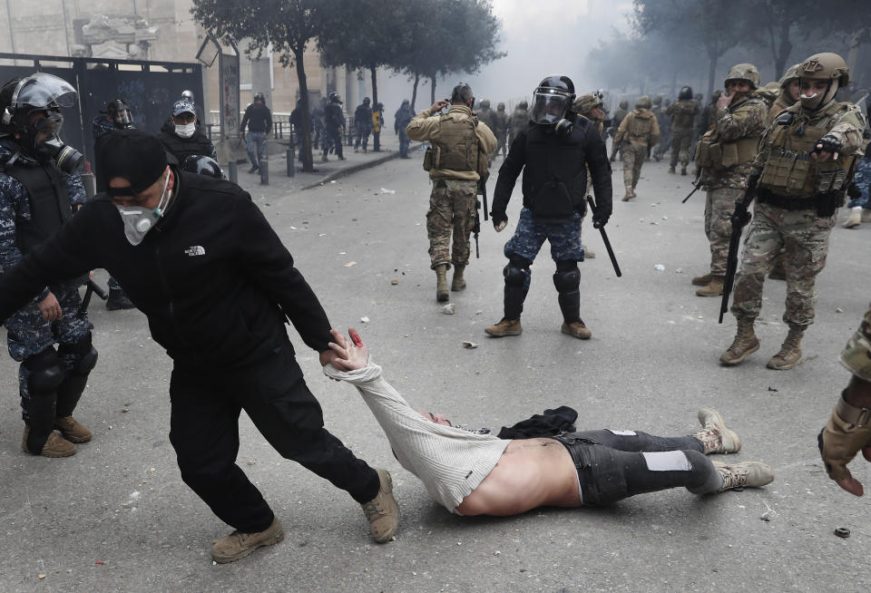 A Lebanese security officer drags an anti-government protester, who was clashing with riot police during a protest, in downtown Beirut, Lebanon,Tuesday, Feb. 11, 2020. Lebanese security forces fired tear gas to disperse thousands of protesters near the parliament building in Beirut, where the new Cabinet was expanding on its policy statement on Tuesday ahead of a confidence vote by lawmakers. (AP Photo/Hussein Malla)