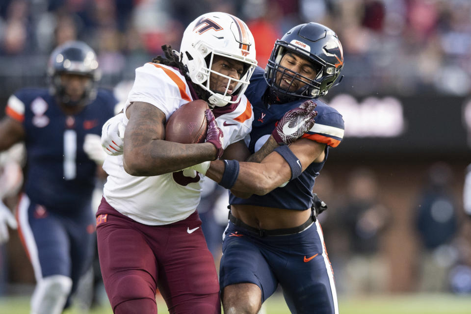 Virginia Tech tight end Dae'Quan Wright (8) is tackled by Virginia safety Jonas Sanker (20) during the first half of an NCAA college football game Saturday, Nov. 25, 2023, in Charlottesville, Va. (AP Photo/Mike Caudill)