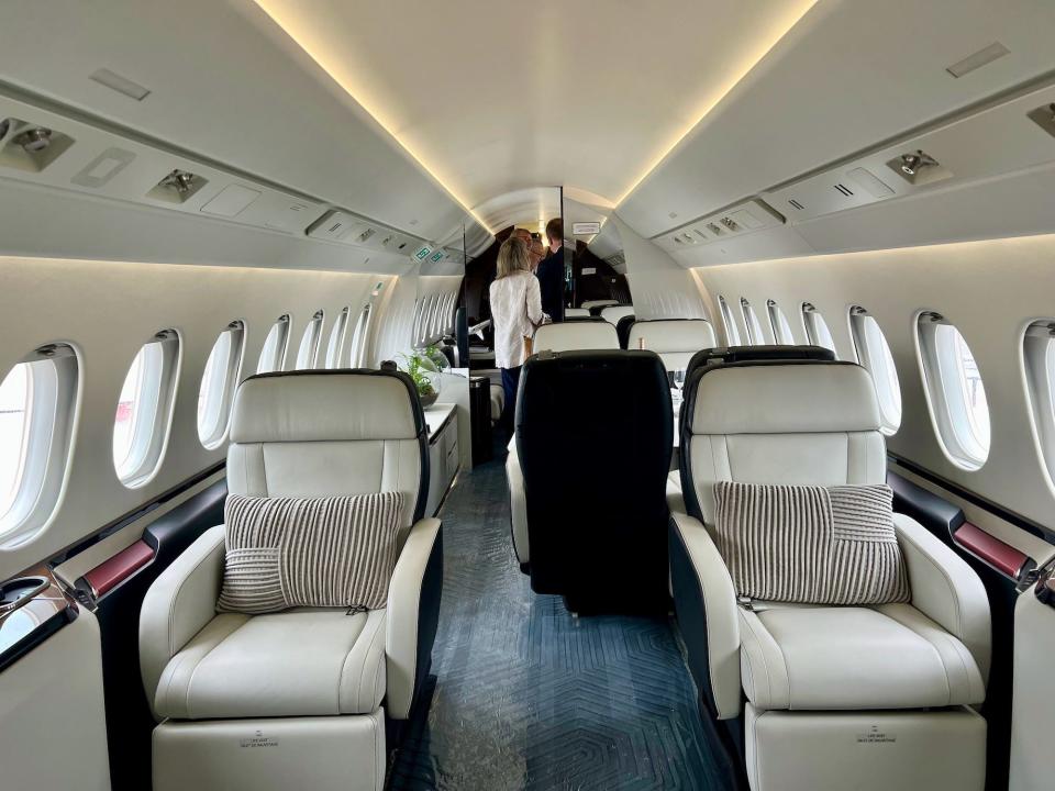 Onboard the 6X private jet with the living room and dining room loungers in view.